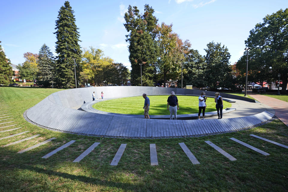 Visitors look over inscriptions on the walls of the Memorial to Enslaved Laborers at the University of Virginia in Charlottesville, Va., Friday Oct. 23, 2020. Devon Henry's company, Team Henry Enterprises, was the general contractor for the recently completed Memorial that honors the enslaved people who built and sustained the Thomas Jefferson-founded university. (AP Photo/Steve Helber)