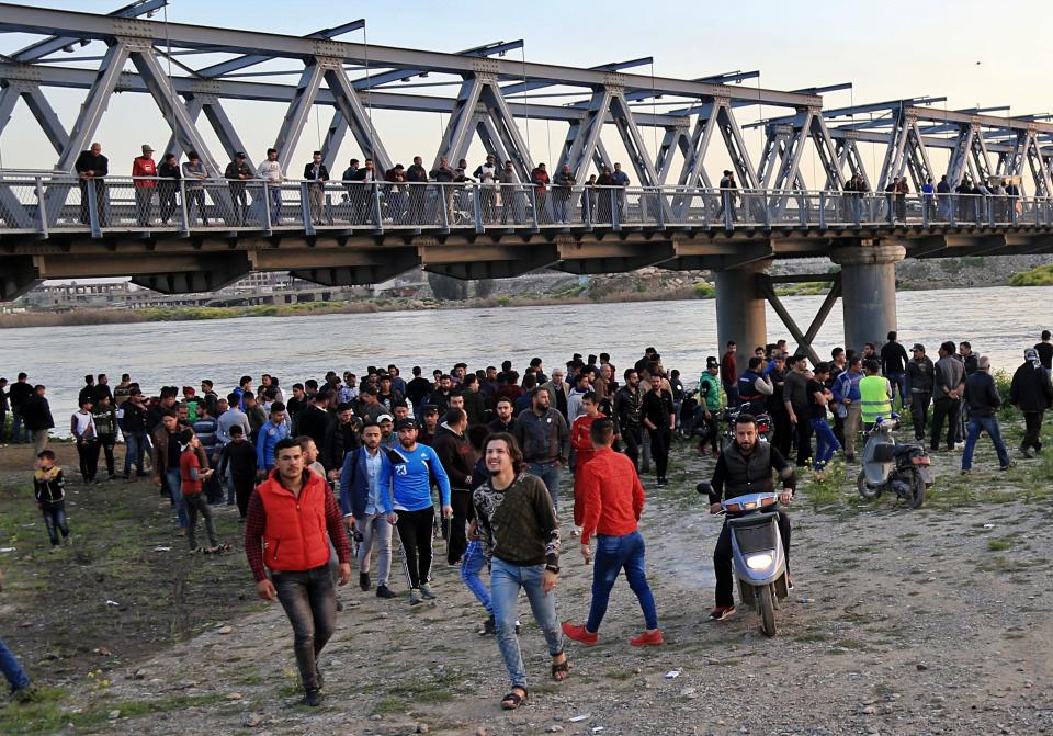 People and relatives of victims waiting on the bank of the Tigris river where the ferry sank in Mosul, Iraq, Thursday, March 21, 2019. A ferry overloaded with people celebrating the Kurdish new year sank in the Tigris River near the Iraqi city of Mosul on Thursday, killing dozens of people, mostly women and children, officials said. (AP Photo/Farid Abdulwahed)