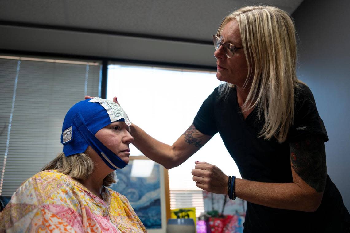TMS technician Stefanie Sizemore jokes with patients that they’re suiting up for a biathalon because during the sessions they wear a tight-fitting cap, like a swim cap, under a helmet. Here she prepares patient Lori Jackson of Overland Park for a 19-minute session.