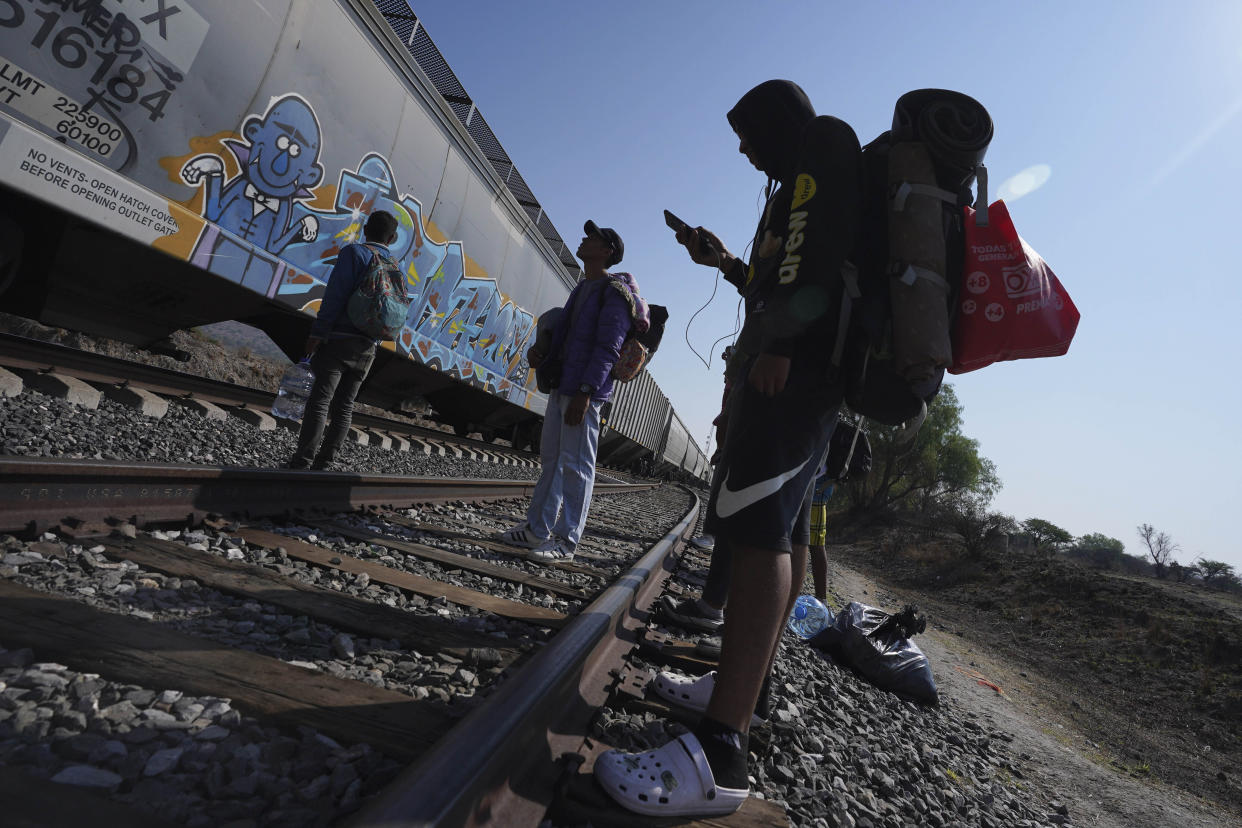 Migrants watch a train go past as they wait along the train tracks hoping to board a freight train heading north, one that stops long enough so they can hop on, in Huehuetoca, Mexico, Friday, May 12, 2023, the day after U.S. pandemic-related asylum restrictions called Title 42 were lifted. (AP Photo/Marco Ugarte)