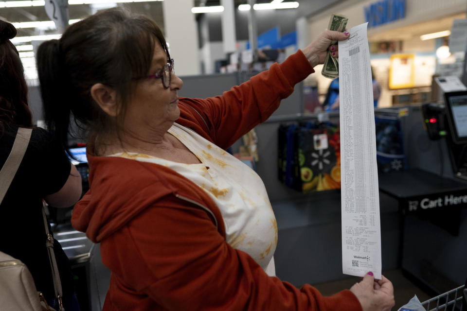 Jodi Ferdinandsen holds up her receipt after checking out with the help of Family Resource Center peer support worker Jesse Johnson at Walmart in Findlay, Ohio, Thursday, Oct. 12, 2023. In addition to peer support, Hancock County has launched recovery housing and college classes on addiction. (AP Photo/Carolyn Kaster)