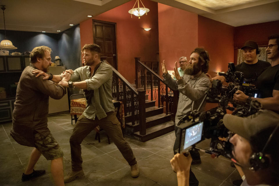 CORRECTS SPELLING OF PHOTOGRAPHER'S FIRST NAME TO JASIN INSTEAD OF JASON - This image provided by Netflix shows actors David Harbour, from left, and Chris Hemsworth being directed by Sam Hargrave for a scene in the action film "Extraction." Hargrave, who was Chris Evans' stunt double on “Captain America” and Hugh Jackman's double on “Wolverine,” is the latest in a lineage of stuntmen who have gone from stepping in for actors to directing them. (Jasin Boland/Netflix via AP)