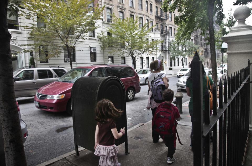 Youngsters walk with their escorts across the street from a shelter on 95th Street on Wednesday, Oct. 3, 2012 in New York. Neighborhood residents are in turmoil, saying they were blindsided by the suddenness of the shelter's opening, sharing the same block as the school. (AP Photo/Bebeto Matthews)