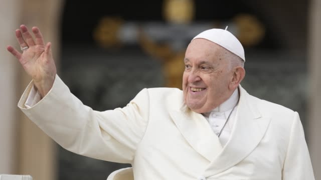 Pope Francis waves a hand.