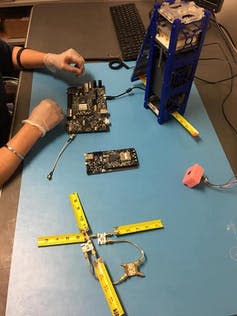<span class="caption">UMass Lowell undergraduate student satellite SPACE HAUC in development. Top right shows a full-scale model of the 3U CubeSat. The tape measures will be used as backup antennas. The protective pink foam covers a small camera that will be used to image the Sun.</span> <span class="attribution"><span class="source">UMass Lowell</span>, <a class="link " href="http://creativecommons.org/licenses/by-sa/4.0/" rel="nofollow noopener" target="_blank" data-ylk="slk:CC BY-SA;elm:context_link;itc:0;sec:content-canvas">CC BY-SA</a></span>
