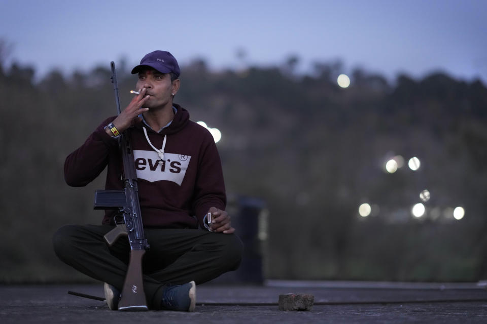 Former Indian army soldier and Village Defense Group member Satish Kumar, smokes sitting on the rooftop of his residence as he guards at Dhangri Village, in Rajouri, India, Feb. 7, 2023. Days after seven Hindus were killed in the village in disputed Kashmir, Indian authorities revived a government-sponsored militia and began rearming and training villagers. The militia, officially called the “Village Defense Group,” was initially formed in the 1990s as the first line of defense against anti-India insurgents in remote villages that government forces could not reach quickly. (AP Photo/Channi Anand)