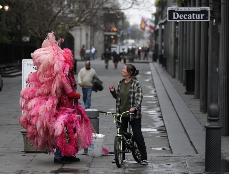 This Jan. 15, 2013 photo shows a man dressed in a Mardi Gras Indian costume talks to a woman on a bicycle along Jackson Square in New Orleans. Artists painting on canvas, clowns making balloon animals, street performers and jazz musicians are among the free entertainment to be found in Jackson Square, a one-block section of the French Quarter anchored by a lush green space with benches set among gardens and grand oak trees. (AP Photo/Gerald Herbert)