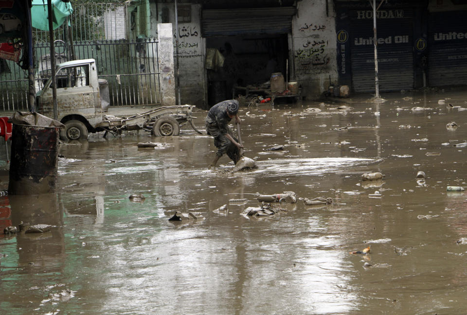 A Pakistani man looks for belongings from his flood-hit shop in Mingora, the capital of Swat valley in Pakistan, Saturday, Aug. 27, 2022. Officials say flash floods triggered by heavy monsoon rains across much of Pakistan have killed nearly 1,000 people and displaced thousands more since mid-June. (AP Photo/Naveed Ali)