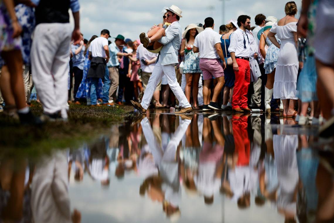 A man carries a woman across a puddle in the infield before the 150th running of the Kentucky Derby at Churchill Downs.