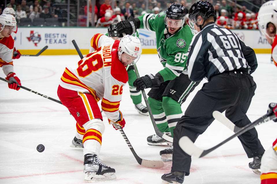 Dallas Stars center Matt Duchene (95) and Calgary Flames center Elias Lindholm (28) battle for the puck in a face off during the first period of an NHL hockey game, Friday, Nov. 24, 2023, in Dallas. (AP Photo/Emil T. Lippe)