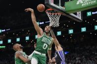 Boston Celtics' Jayson Tatum (0) and Sacramento Kings' Trey Lyles, right, reach for a rebound during the first half of an NBA basketball game Friday, April 5, 2024, in Boston. (AP Photo/Michael Dwyer)