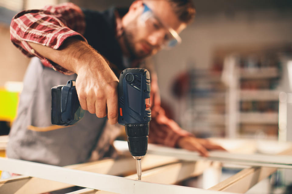 Young man working with drill in the workshop