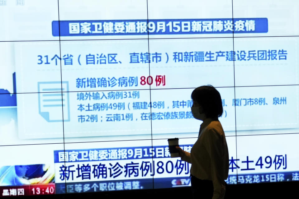 A woman wearing a face mask to help curb the spread of the coronavirus is silhouetted as she walks by a TV screen showing CCTV reporting number of COVID-19 cases in China, at a shopping mall in Beijing, Thursday, Sept. 16, 2021. (AP Photo/Andy Wong)