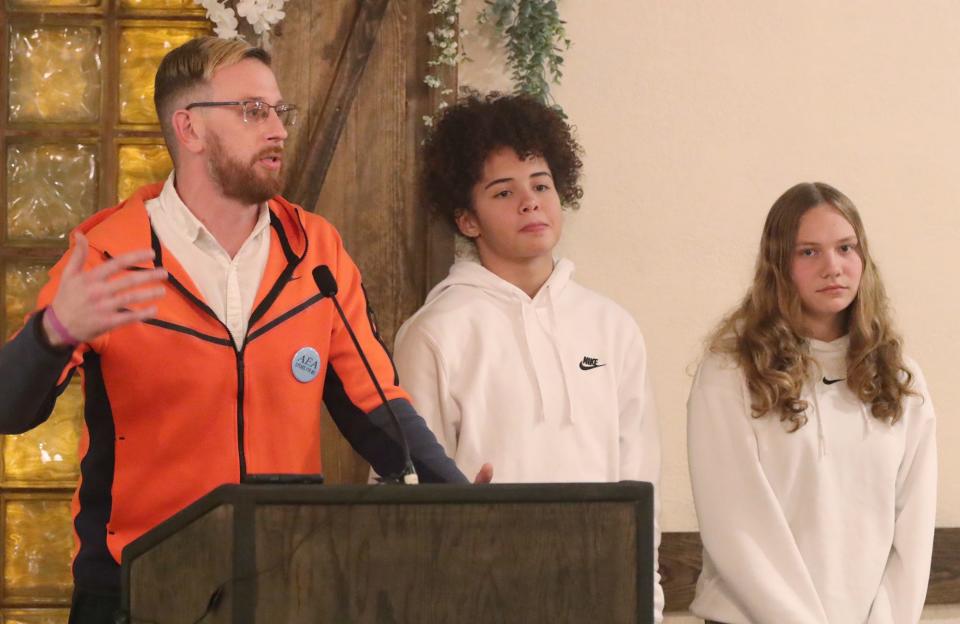 Ellet girls basketball coach Nick Harris speaks as his players Caitlyn Holmes and Rachel Wenzel listen during the Akron Public Schools City Series Basketball Media Day at Guy's Party Center in Akron on Tuesday.