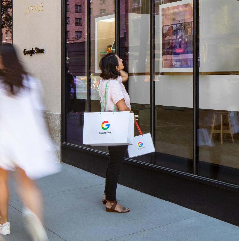 <p>Google Store Chelsea. A person outside the store carrying two Google-branded shopping bags looks at one of the displays facing the street.</p> 