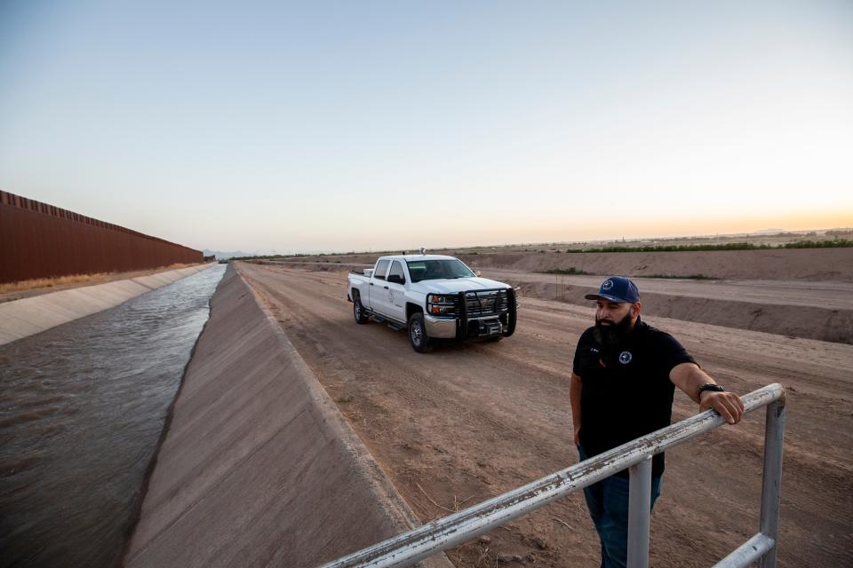 Enrique Perez, a supervisor for the El Paso County Water Improvement District No. 1 is a younger employee of the water district but has already had to see several deaths of migrants in the canals. In this photo, he stands near the canal with the border wall to the south in the lower valley of El Paso, Texas in June 2023.