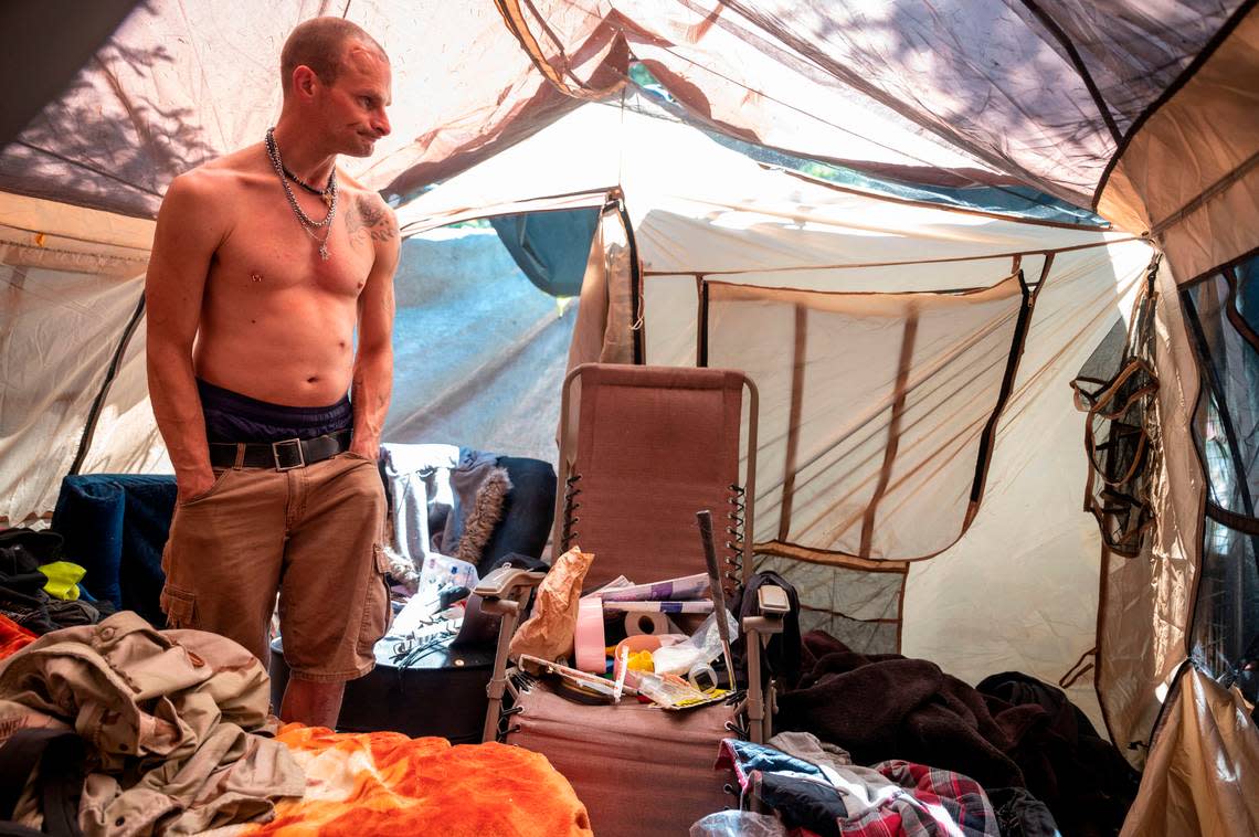 Brandon Jermaine Lee Booker, also known as “Bullet,” stands inside the sleeping area of his tent inside the homeless encampment just east of the 9700 block of Steele Street South in Tacoma on Thursday, May 25, 2023. Booker could remember a time 10 years ago when only three people lived in the privately-owned wooded area on the far south end of Tacoma.