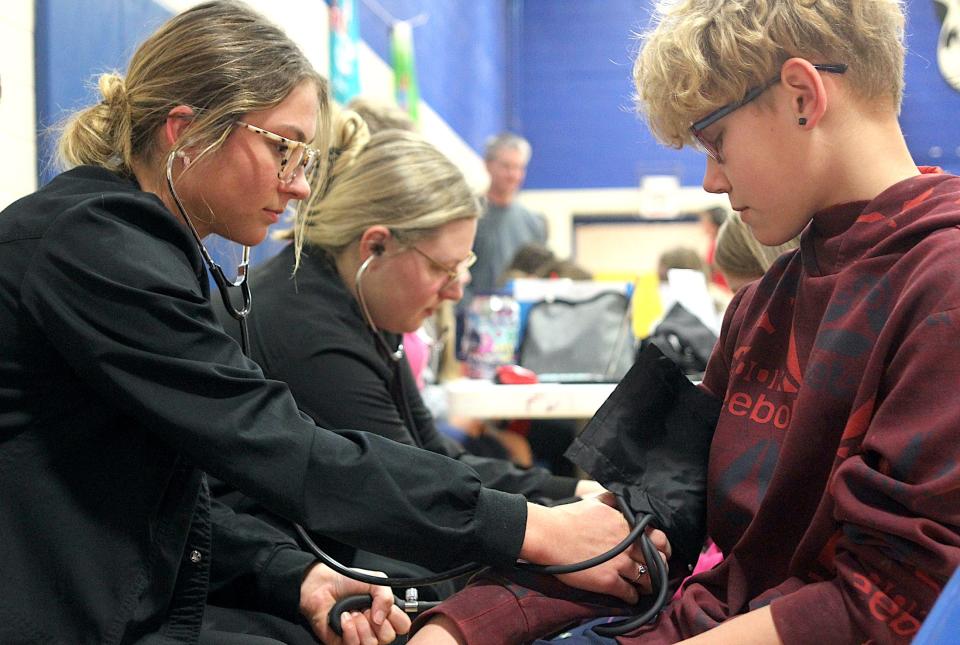 Health science student Katie Godlevske takes Lincoln Elementary student Vincente Mack's blood pressure Tuesday, March 19, 2024, at Parkview Intermediate School.
