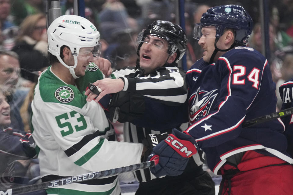 Linesman James Tobias, center, gets between Dallas Stars center Wyatt Johnston (53) and Columbus Blue Jackets right wing Mathieu Olivier (24) in the third period of an NHL hockey game Thursday, Nov. 9, 2023, in Columbus, Ohio. (AP Photo/Sue Ogrocki)