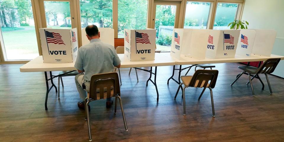 A voter sits alone at a poll kiosk to cast his vote at a Mississippi Second Congressional District Primary election precinct, June 7, 2022, in Jackson, Miss.