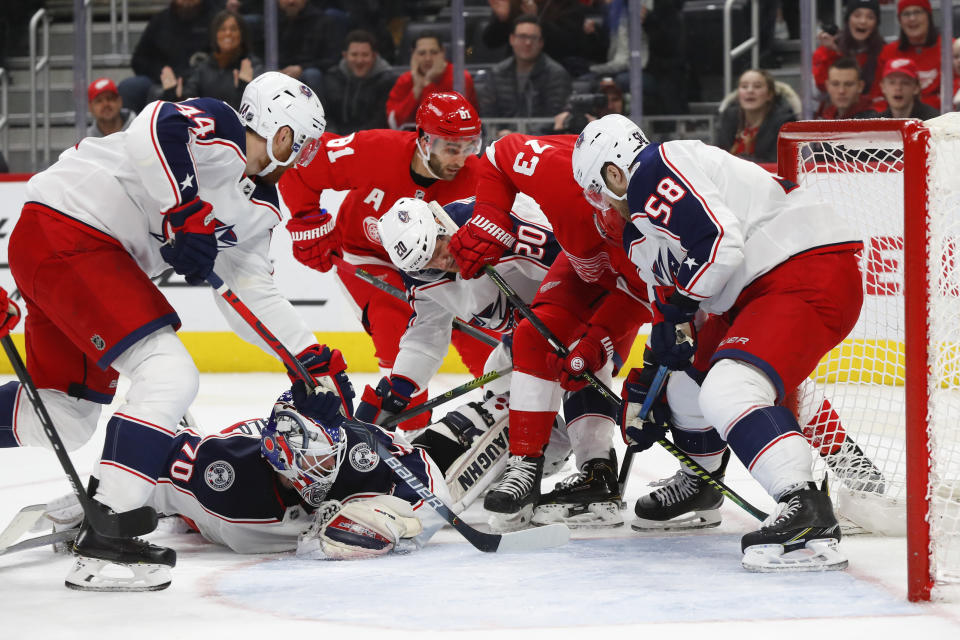 Columbus Blue Jackets defenseman David Savard (58) keeps the puck out of the net as goaltender Joonas Korpisalo (70) is out of position against the Detroit Red Wings in the second period of an NHL hockey game Tuesday, Dec. 17, 2019, in Detroit. (AP Photo/Paul Sancya)
