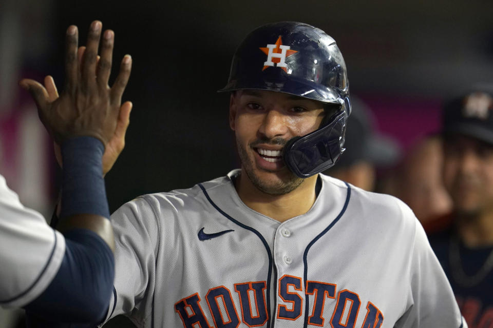 Houston Astros' Carlos Correa is greeted in the dugout after scoring on a two-run home run by Kyle Tucker during the second inning of a baseball game against the Los Angeles Angels Tuesday, Sept. 21, 2021, in Anaheim, Calif. (AP Photo/Marcio Jose Sanchez)