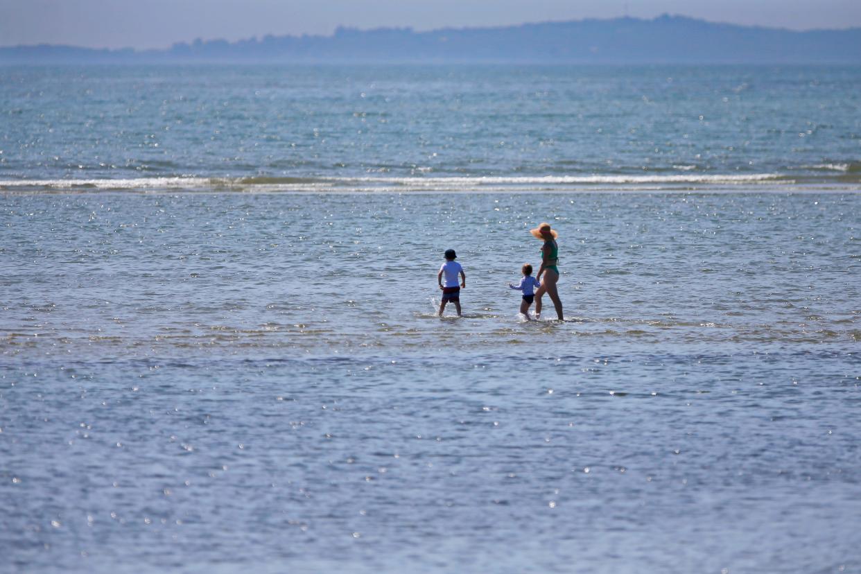 A woman and two young children take advantage of the low tide to walk far out on the sandbar at the Demarest Lloyd State Park in Dartmouth.