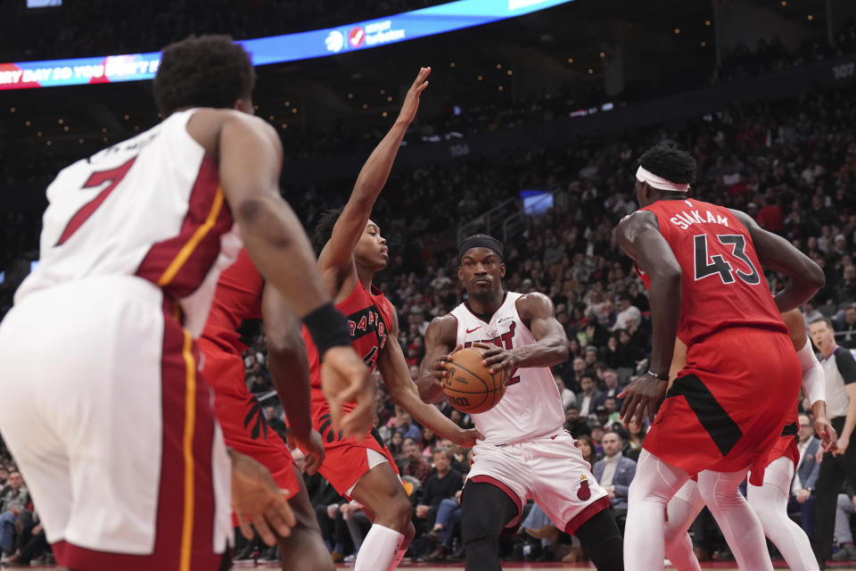 Miami Heat's Jimmy Butler, centre, looks to pass despite pressure from the Toronto Raptors defense during the second half of an NBA basketball game, Wednesday, Dec. 6, 2023 in Toronto. (Chris Young/The Canadian Press via AP)