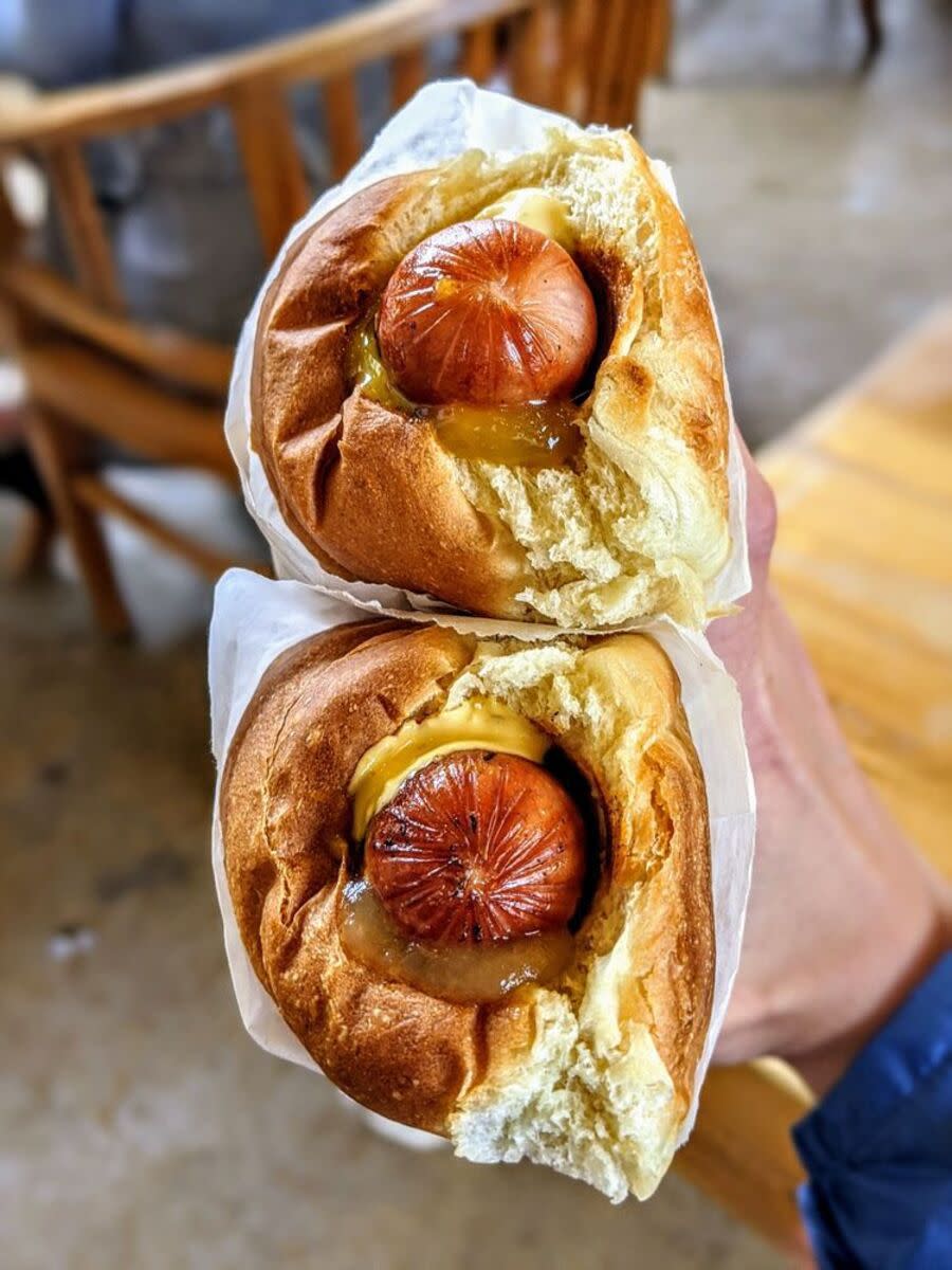 Two Polish sausages with hot chili pepper sauce, pineapple relish, lilikoi mustard (top) and lava habanero sauce, mango relish, lilikoi mustard (bottom), both in King's Hawaiian buns at Puka Dog, Poipu Beach, Hawaii