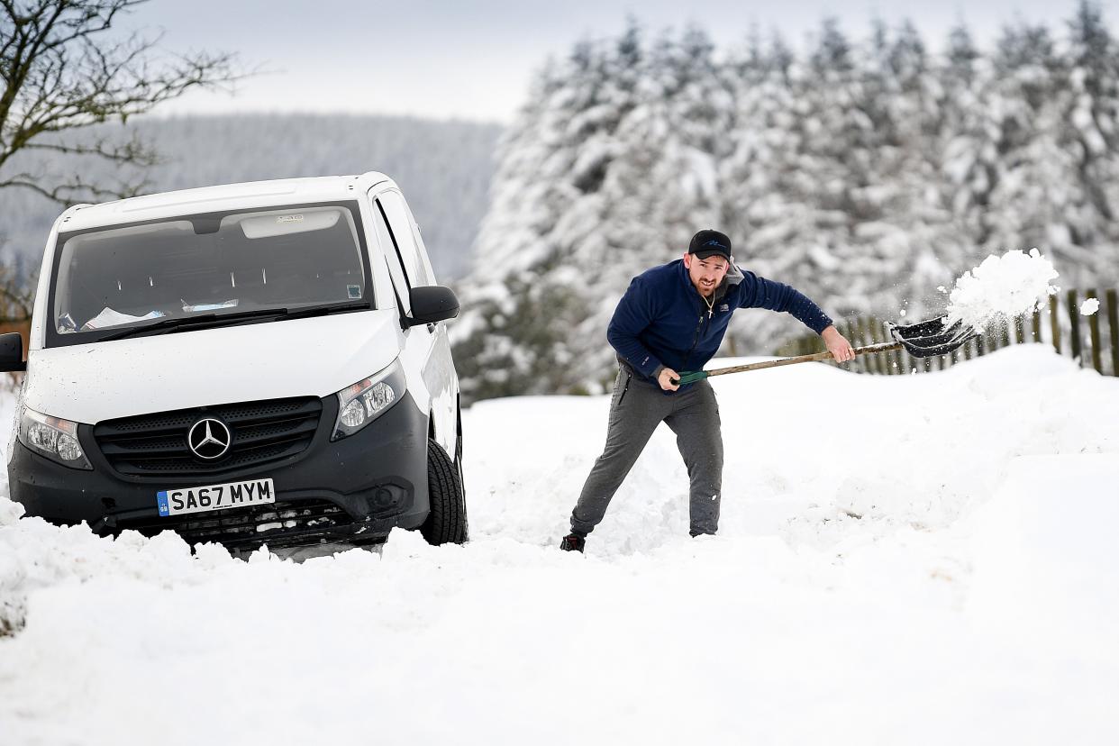 <p>A man clears snow from around a van which became stuck in a snow drift in Lamancha, Scotland</p> (Getty Images)