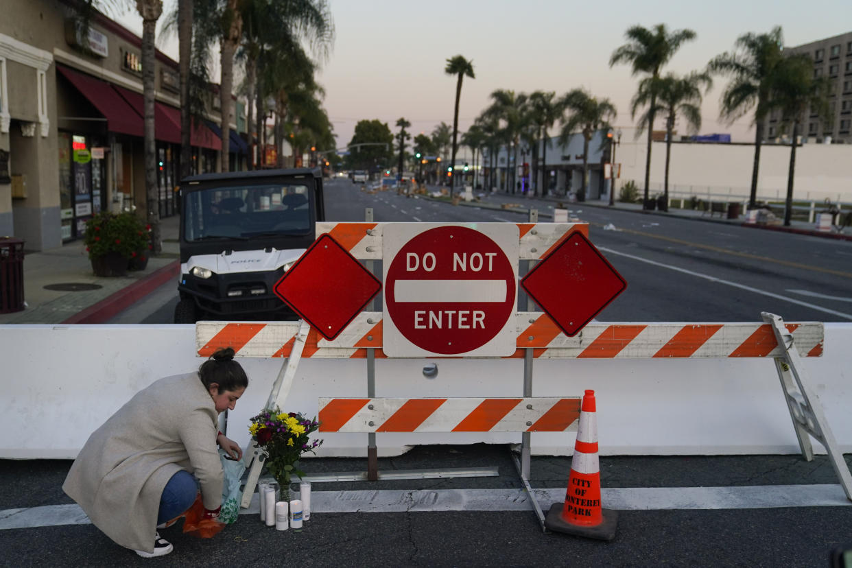 A woman leaves flowers and candles to honor the victims killed in Saturday's ballroom dance studio shooting in Monterey Park, Calif., Sunday, Jan. 22, 2023. (AP Photo/Jae C. Hong)