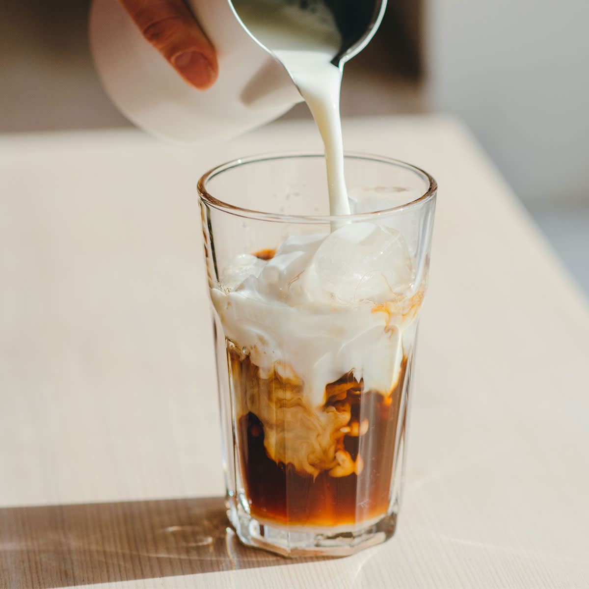 creamer being poured into iced coffee