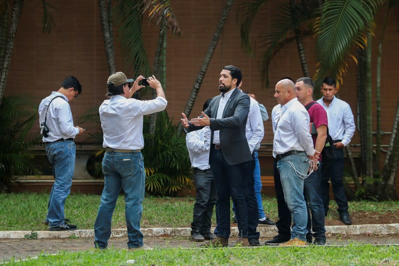 Supporters of Venezuela's opposition leader Juan Guaido record a video from the grounds of the Venezuelan embassy in Brasilia