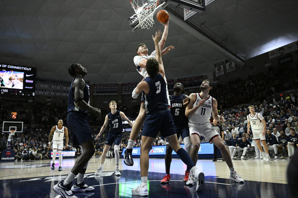 UConn center Donovan Clingan, top, makes a basket over New Hampshire's forward Jaxson Baker (3) in the first half of an NCAA college basketball game, Monday, Nov. 27, 2023, in Storrs, Conn. (AP Photo/Jessica Hill)