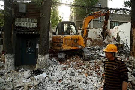 FILE PHOTO: An excavator demolishes a house in a hutong neighborhood near the Forbidden City in Beijing, China April 20, 2017. REUTERS/Thomas Peter/File Photo