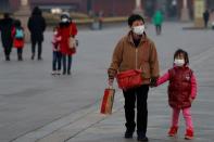 People wearing face masks walk at the Tiananmen Gate, as the country is hit by an outbreak of the new coronavirus, in Beijing