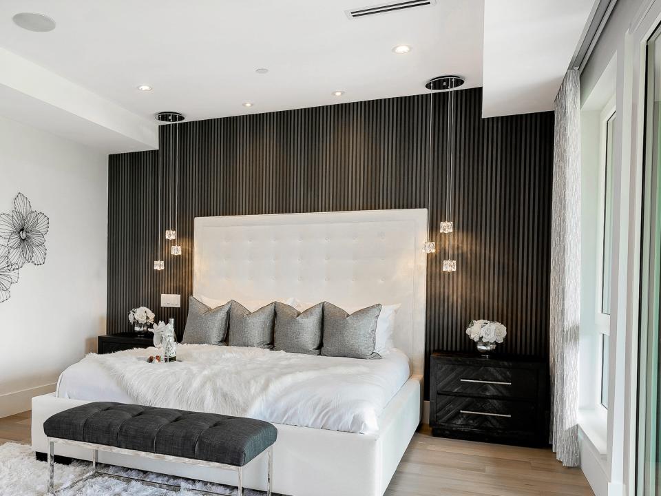 Bed with white sheets and dark brown accent wall behind it