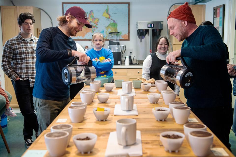 Matthew McDaniel, left, and Eli Masem pour hot water over coffee grounds during their monthly cupping event, January 19, 2024. Guests are encouraged to smell and taste a variety of coffees.