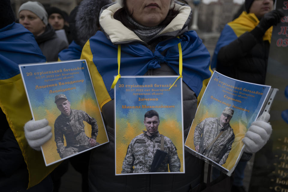 A Ukrainian woman holds up pictures of missing soldiers during a demonstration in downtown Kyiv, Ukraine, Saturday, Jan. 14, 2023. (AP Photo/Bela Szandelszky)