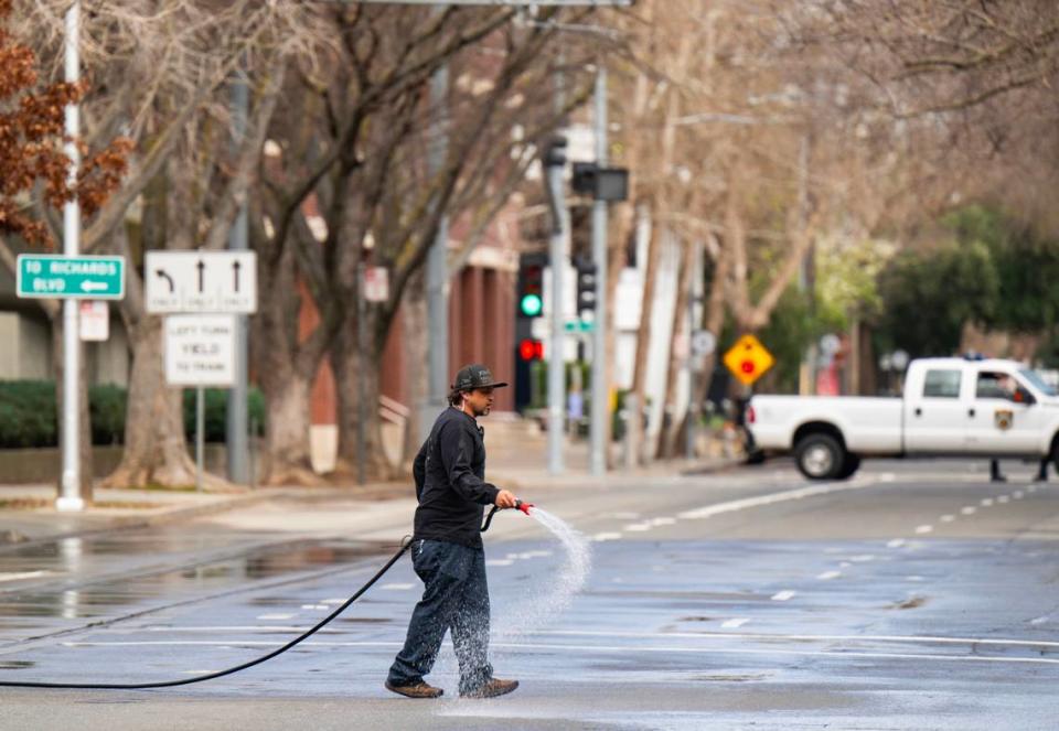 A crew member wets down H Street, closed for filming, in downtown Sacramento in preparation for a scene in director Paul Thomas Anderson’s upcoming movie on Saturday.