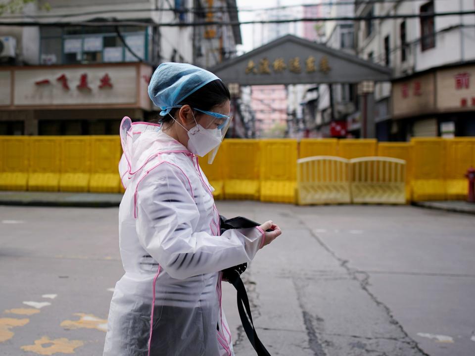 FILE PHOTO: A woman wearing a face mask walks at a residential area blocked by barriers in Wuhan, Hubei province, the epicentre of China's coronavirus disease (COVID-19) outbreak, April 3, 2020. REUTERS/Aly Song