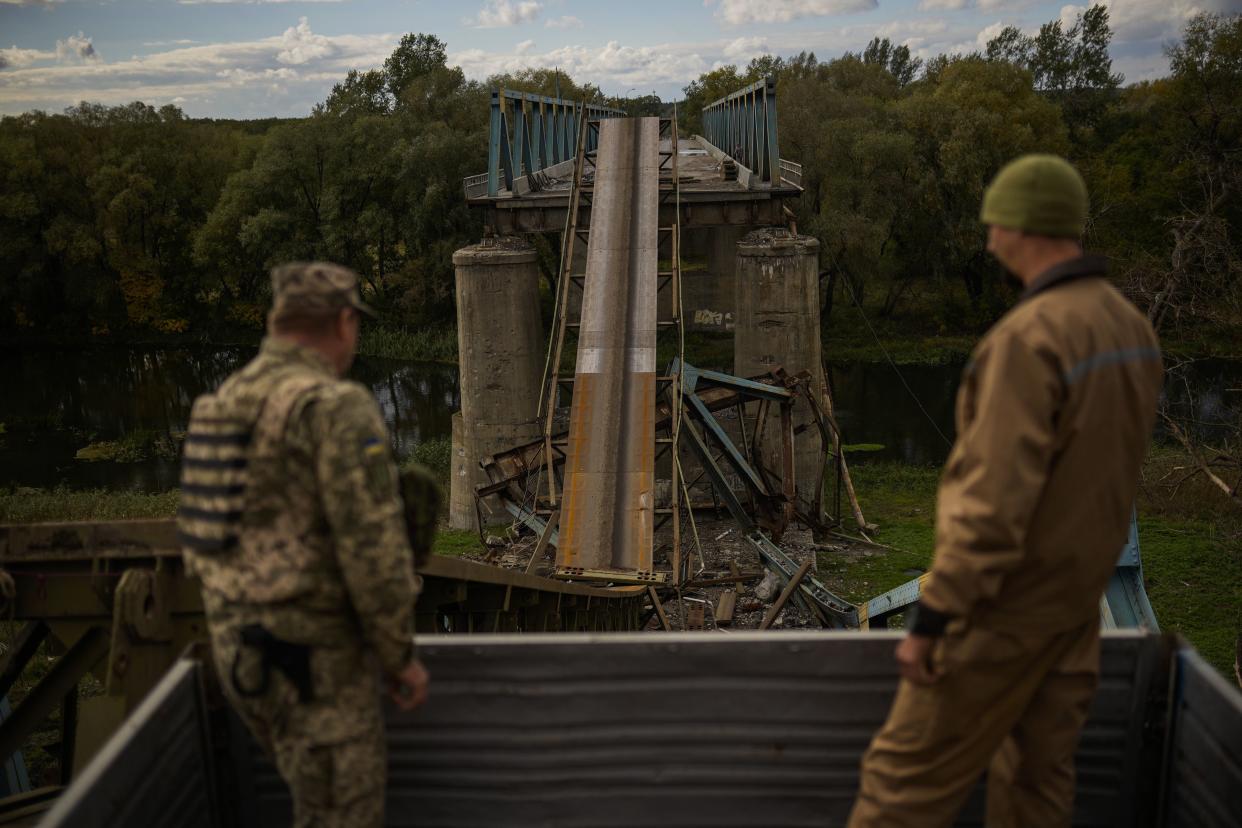 Ukrainian soldiers remove metal structure pieces as they work on a bridge damaged during fighting with Russian troops in Izium, Ukraine, Monday, Oct. 3, 2022. 