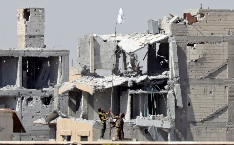 Des combattants des Forces démocratiques syriennes (FDS) lèvent un drapeau blanc près d'un complexe de l'hôpital national. Les FDS ont annoncé mardi la prise de l'Hôpital national de Rakka, l'un des derniers bastions de l'Etat islamique dans l'ancienne capitale autoproclamée du groupe djihadiste en Syrie. /Photo prise le 16 octobre 2017/REUTERS/Erik De Castro