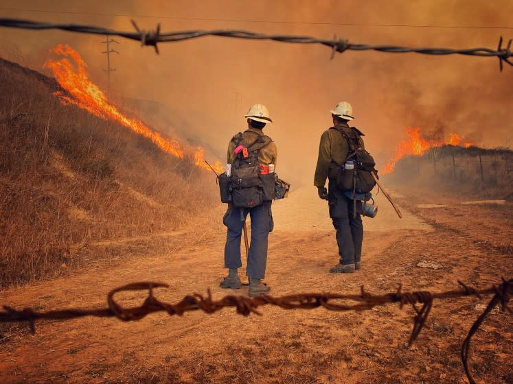 This Tuesday Oct. 12, 2021, photo provided by Santa Barbara County Fire, Santa Barbara County Fire Hand Crew members fight fire with fire and burn off pockets of grass along northbound Highway 101 north of Arroyo Hondo Canyon in Santa Barbara County, Calif. The Alisal Fire with erupted Monday has scorched more than 9 square miles (23 square kilometers) by early Tuesday and remained completely uncontained. Evacuation orders were issued for several areas of the lightly populated region. (Mike Eliason/Santa Barbara County Fire via AP)