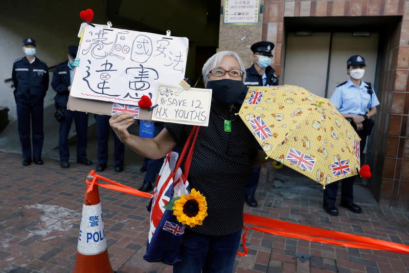 Pro-democracy activist Alexandra Wong holds placards during a protest to urge for the release of 12 Hong Kong activists outside China's Liaison Office, in Hong Kong