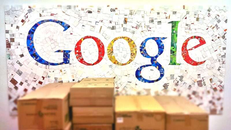 The google logo on a wall with packing boxes in front of it