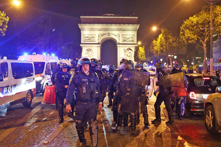 Agentes de la policía francesa patrullan frente al Arco del Triunfo en la zona de los Campos Elíseos de París el 1 de julio de 2023, cinco días después de que un joven de 17 años muriera a manos de la policía en Nanterre, un suburbio del oeste de París.