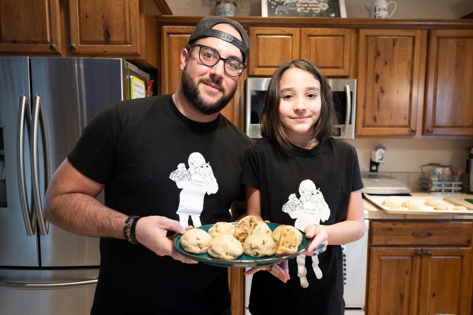 Christapher Garcia and his daughter Kennedi show off a fresh-baked batch of Kennadi's Kookies at their home on Tuesday, Dec. 20, 2022.