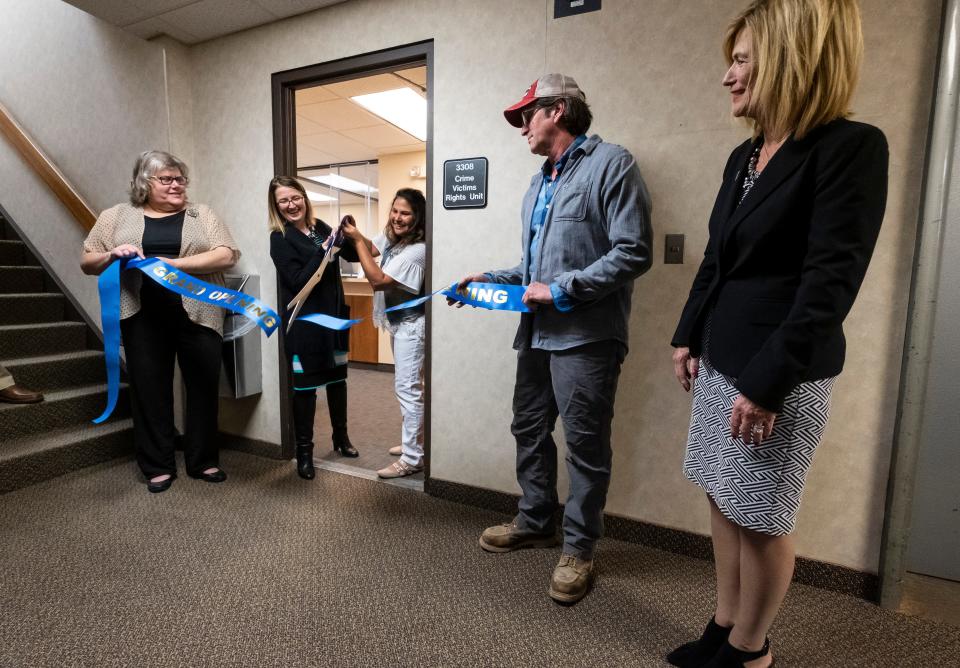 Mara McCalmon, center, a violent crime survivor and founder of P.S. You're My Hero, cuts the ribbon for the P.S. You're My Hero Comfort Room with victims rights advocate Cortney Carl, second from left, during a ceremony held Friday, April 12, 2019 at the St. Clair County Courthouse.