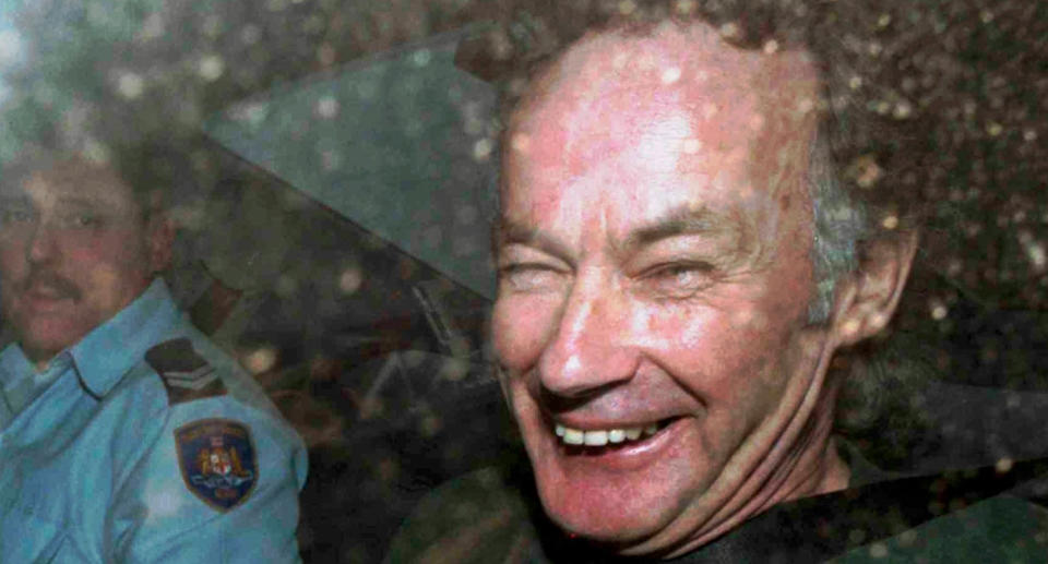 Serial killer Ivan Milat pictured in a 2014 file photo with a police officer in back of a car.